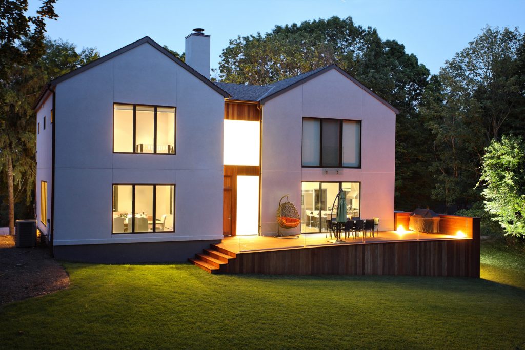 Installed aluminum windows and doors on a white house taken at dusk with the lights on in the home.
